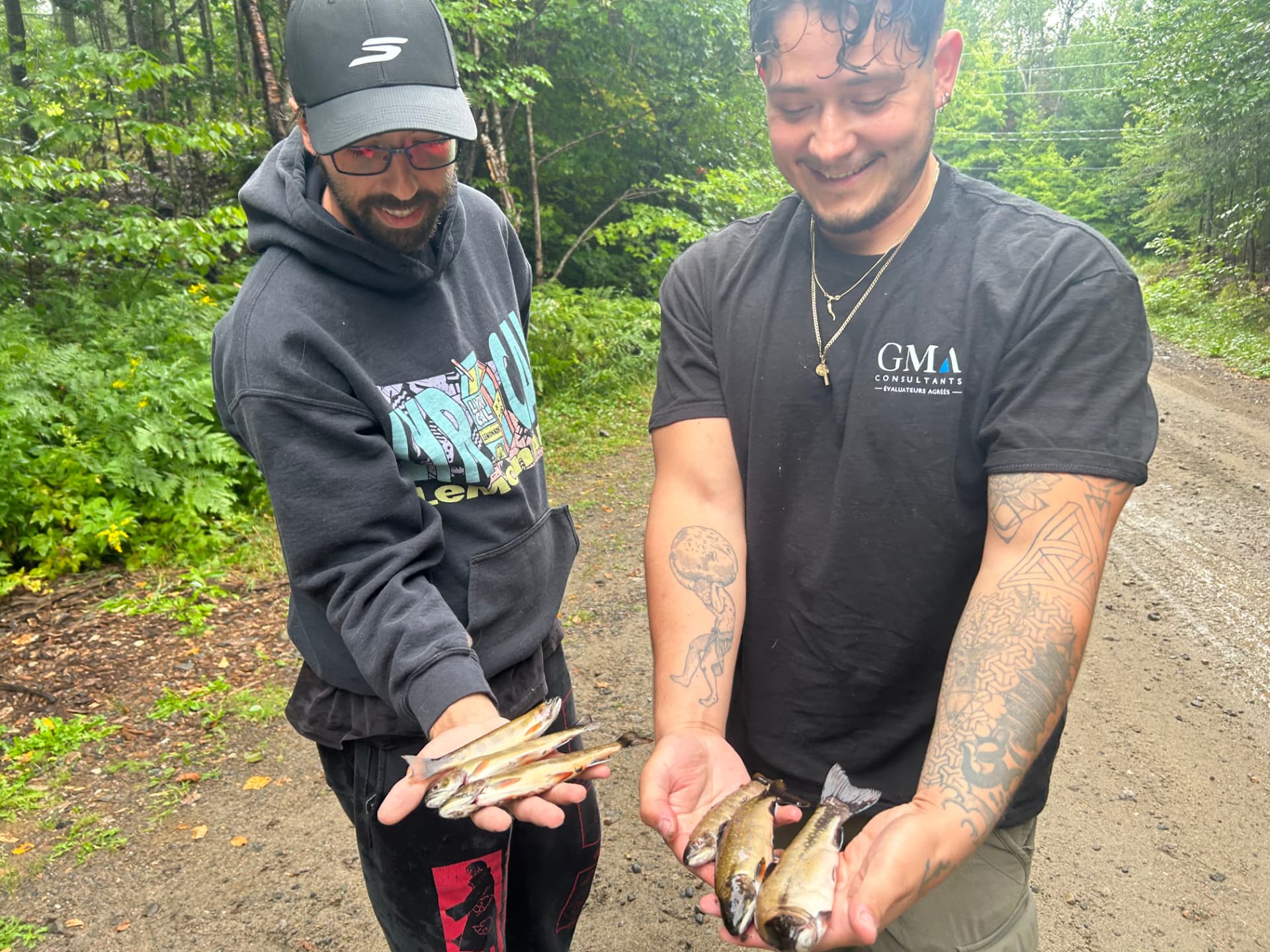 Deux pêcheurs tenant leurs truites mouchetées dans leurs mains sur un chemin forestier des Laurentides